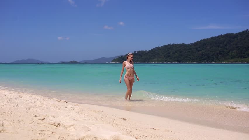 Beach bikini woman walking into ocean swimming in the sea on vacation travel getaway holidays. Beautiful young multiracial Asian Caucasian female model, 20s. Koh Lipe, Thailand