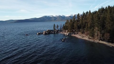 drone flys along a shore line of lake tahoe california, california. drone flys by chimney beach. clear skies.