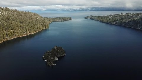 drone flys over emerald bay with fannett island to the left. drone flys straight with lake tahoe in the horizon