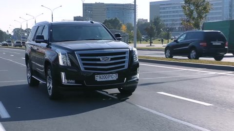MINSK, BELARUS - AUGUST 20, 2017: Black new shiny Cadillac Escalade 6.2 V8 drives on a road on a sunny day. Escalade is a full-size luxury SUV, most most identifiable model of Cadillac.