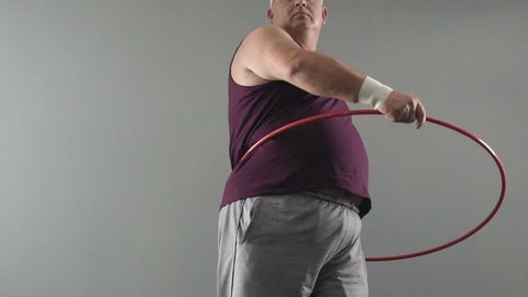 Obese male trying to twist hula hoop, dreams of healthy and fit body, weightloss