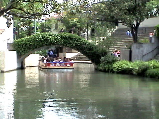 San Antonio Texas Riverwalk. Tourist barges floating down river. Guide describing scenes. Near outdoor theater.