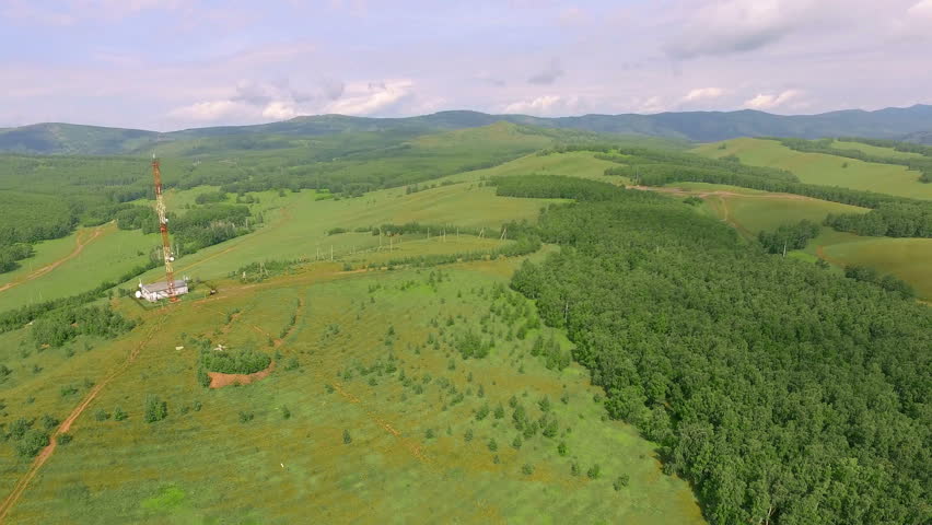 AERIAL: The radio tower at the top of the mountain. Communication antenna among nature landscape during summer. Green terrain and blue skies.