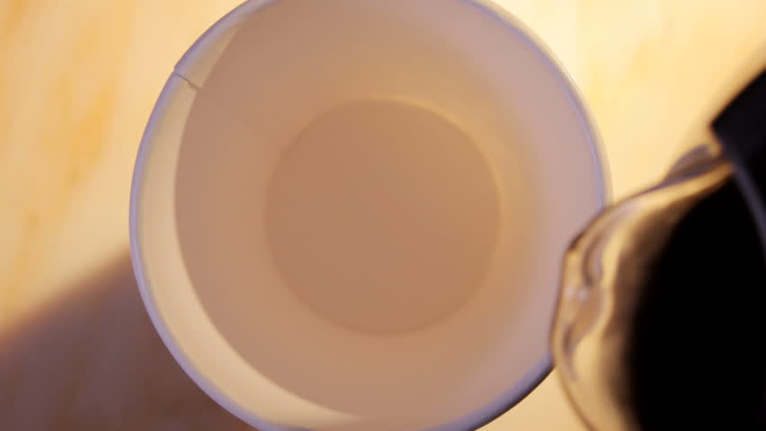 close up HD video of coffee and milk pouring into paper cup, hand takes cup away