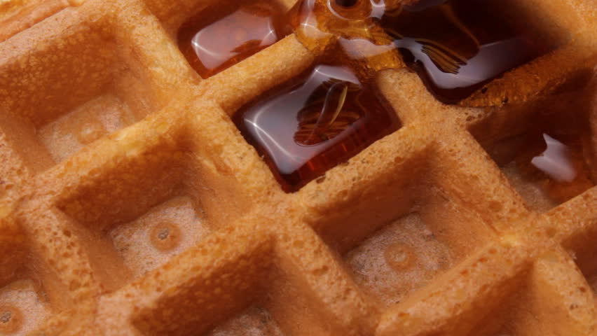 Pouring maple syrup on a waffle