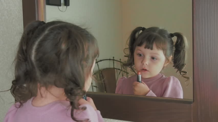 Little fashion-girl. Little girl at the mirror with lipstick.