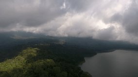 Aerial video of cloudy sky and mist over island coastline covered with green jungle trees, footage of wet climate conditions in tropical lands washed with ocean and dramatic cloudscape above