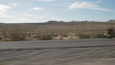 Driving plate side view moving through desert in car empty road