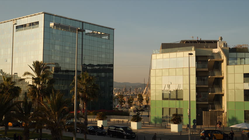Modern, glass buildings at the coast of Barcelona, in stark contrast with the old city behind them.