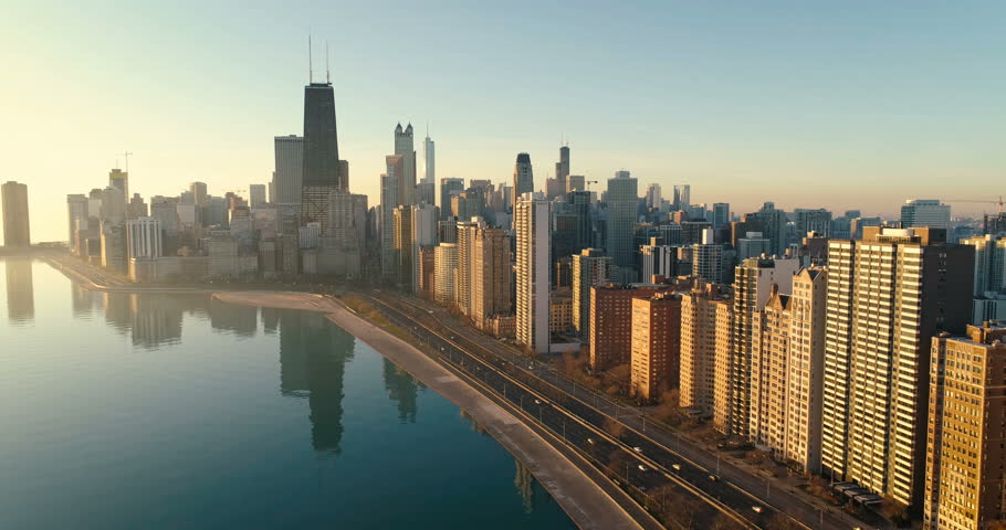 Flying above Chicago Downtown skyline at sunrise. Road by the shore with cars