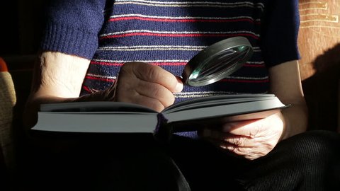Grandmother reading a book with a magnifying glass