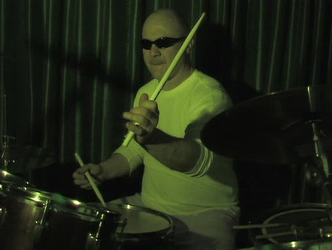 CLOSE-UP OF MAN ON STAGE PLAYING DRUMS WITH STROBE LIGHT EFFECT. (DV NTSC)