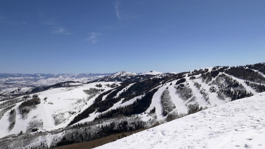 Wide shot of family skiing to edge of Pioneer Ridgeline to look at views of Park City Mountain, Utah with ski runs and Motherlode, Thaynes, and King Con lifts.
