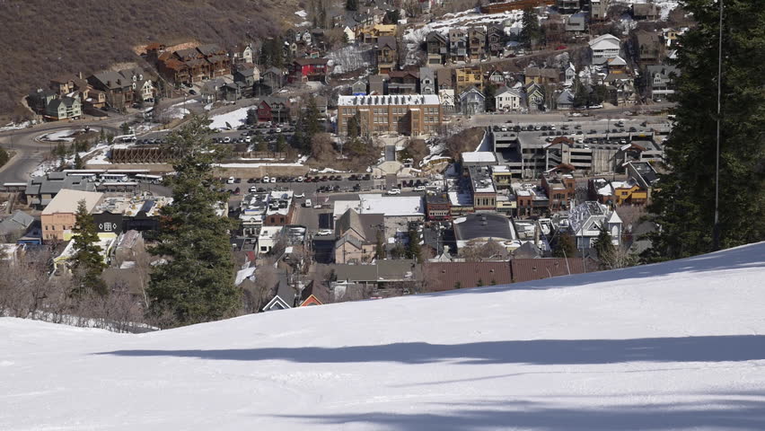 Family of five including three sons skis down the Town Lift run toward historic Park City old town on sunny, winter day at Park City, Utah.
