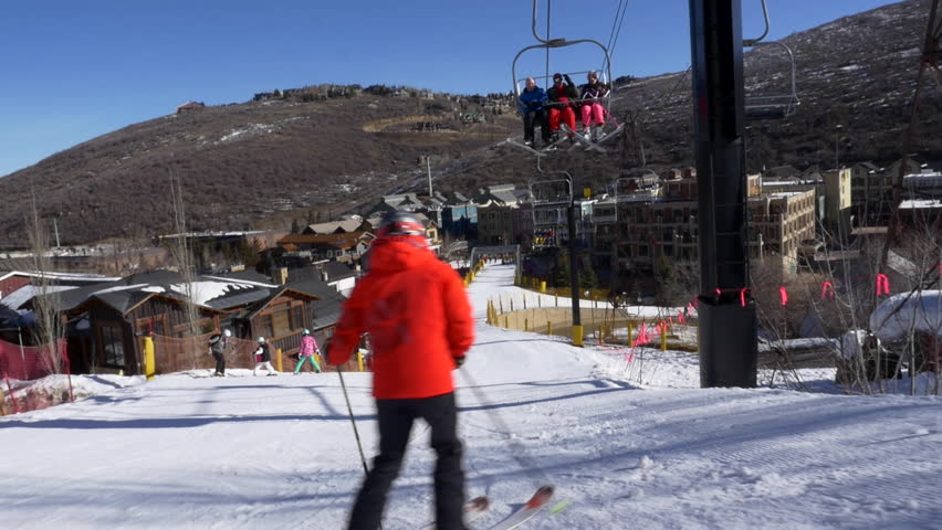 Family of five including three sons skis down the Town Lift run toward historic Park City old town on sunny, winter day at Park City, Utah.
