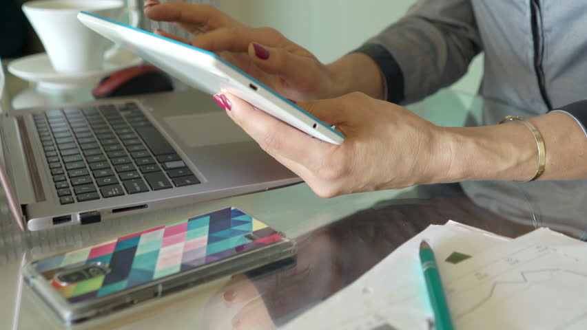 Businesswoman using tablet computer sitting by table in office 
