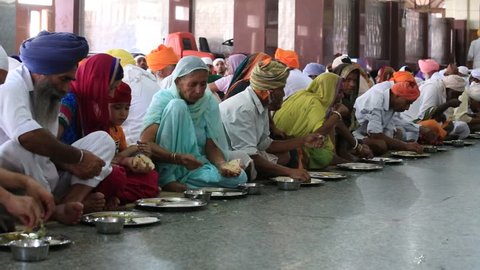 AMRITSAR, INDIA - SEPTEMBER 29, 2014: Unidentified poor indian people receive a free meal inside the 'langar', a communal kitchen on the famous Sikh Golden Temple complex in Amritsar.