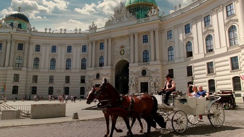 A viennese Coach, so called „Fiaker“ passes by at the Michaelerplatz at this wide angle shot of the „Wiener Hofburg“, Sky is replaced.

Variation without: "Vienna Hofburg  with Fiaker - tilt up".