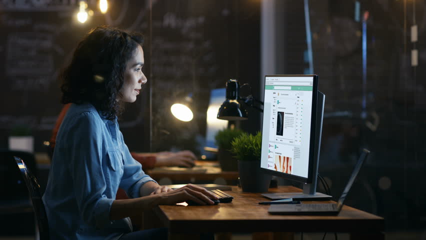 Beautiful Female Office Worker Browsing Social Networks Site, Scrolling Web Page Wall. Her Colleague Sits in the Background in this Creative Office.   Royalty-Free Stock Footage #33749674