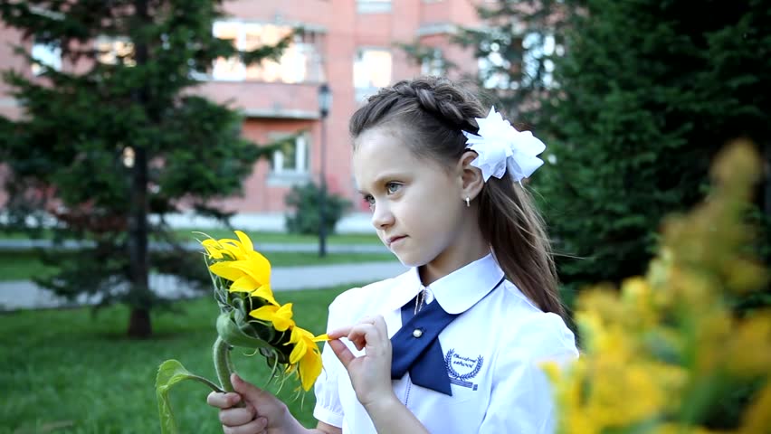 girl in school uniform in the Park looking at the sunflower