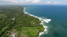 Aerial video of beautiful landscape of green island coastline during summer season.Bird's eye view of turquoise water of sea and waves on shore