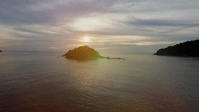 Full HD real time Aerial Footage of a small island in silhouette view during the sunrise with amazing ray of light and sun flare.