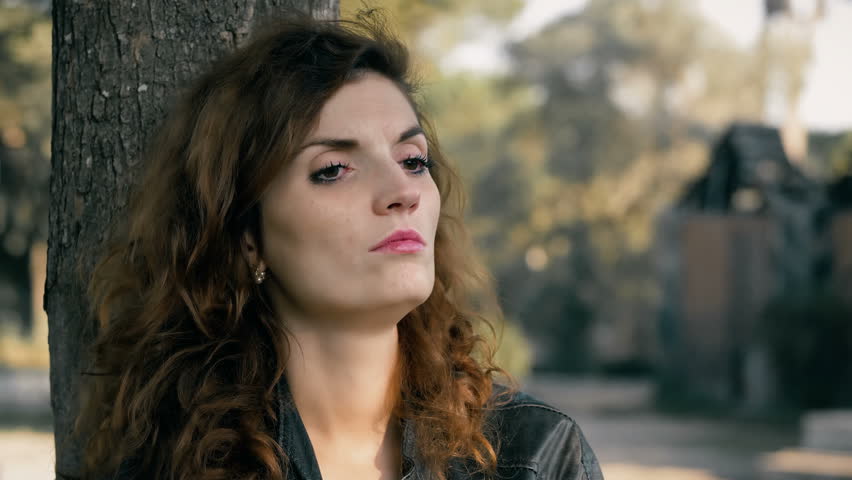 pensive and sad woman thinking under a tree. She has just been fired