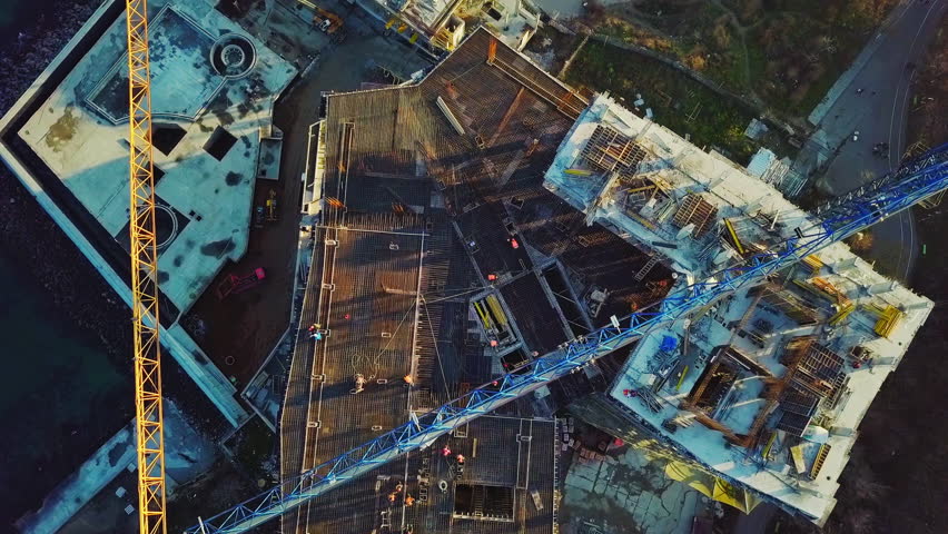 Aerial city view. Construction of a high-rise skyscraper on the ocean by two cranes. The camera is pointing down. Flies horizontally from the subject. Royalty-Free Stock Footage #33764056