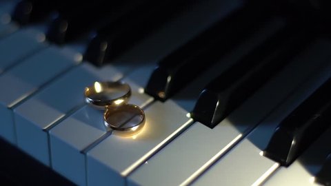 Wedding rings on piano keys. Point source of light.