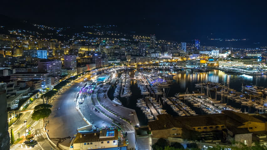 Panorama of Monte Carlo timelapse hyperlapse at night from the observation deck in the village of Monaco with Port Hercules. Buildings with illumination and yachts in harbor aerial top view. Traffic