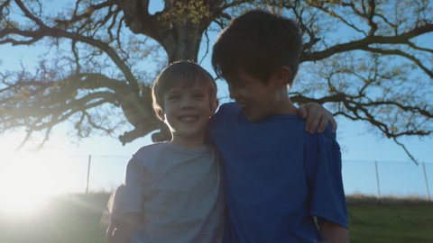 Two Boys / Brothers / Best Friends hugging and looking at camera
