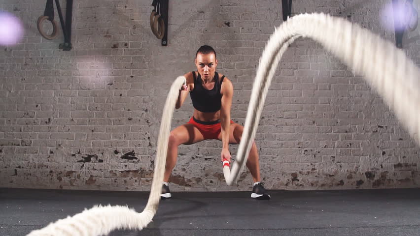 Athletic Female Actively in a Gym Exercises with Battle Ropes During Her Cross Fitness Workout. Slow motion | Shutterstock HD Video #33774547