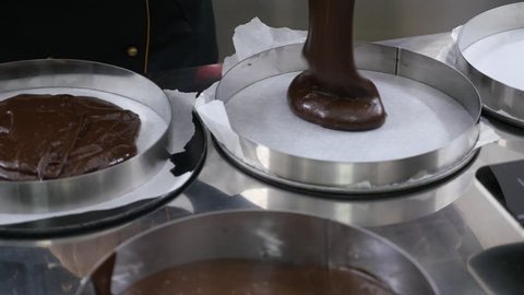 A confectioner making a cake base, she pours the mixture into cake pans...