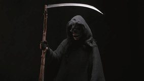 Grim reaper dancing with his scythe. Studio portrait on black background. Symbolism and superstition. Costume for Halloween. Halloween characters concept. - Powered by Shutterstock - Get 15% off with code: PIKWIZARD15