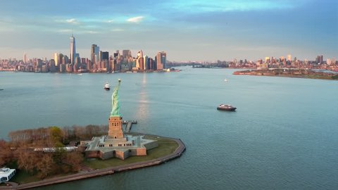  Aerial view of the Statue of Liberty at sunset. Manhattan and New Jersey skyline in the background. New York City, United States. Shot from a helicopter.