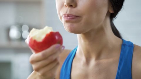 Girl eating apple replenishing her body with vitamins after grueling workout