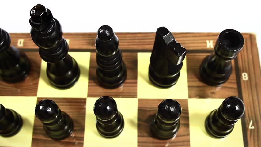 Black chess pieces lined up. Chess pieces lined up on the first rank. Camera pan