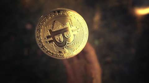 Hand flipping golden bitcoin coin and catching it. Slow motion, closeup.