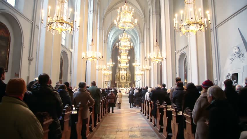 people in Sacred Augustines church stand during worship service on Vienna, Austria.