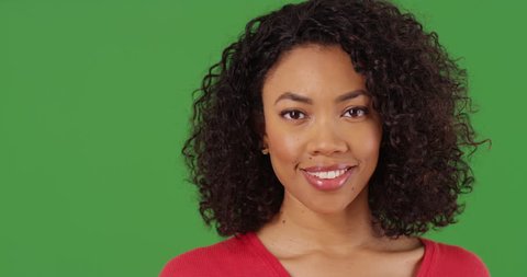 Close up portrait of pretty black woman smiling and looking at camera on greenscreen background. Close-up of cheerful African American millennial on green screen for keying or compositing. 4k