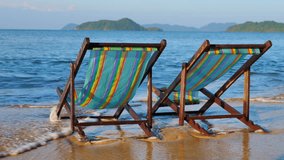 Advertising,Travel, Vacation and Holiday Concept - Pair of Beach chairs on the white sand and Bubble of Sea wave on the beach.