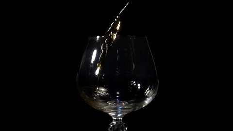 Cognac is poured into a glass in Slow Motion on a black background
