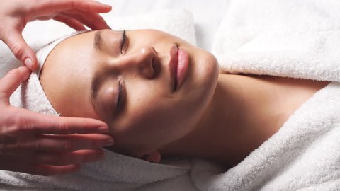 Spa woman facial Massage. Face Massage in beauty spa salon. Female enjoying relaxing face massage in cosmetology spa centre. Body care, skin care, wellness, beauty treatment.