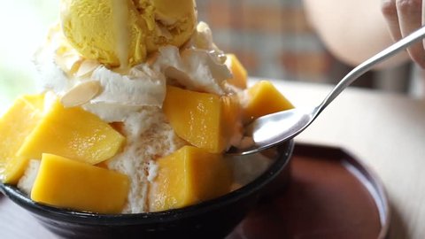 Mango shaved ice, also known as Bingsu Korean dessert, served with sticky rice, whipped cream and mango ice cream on the table.