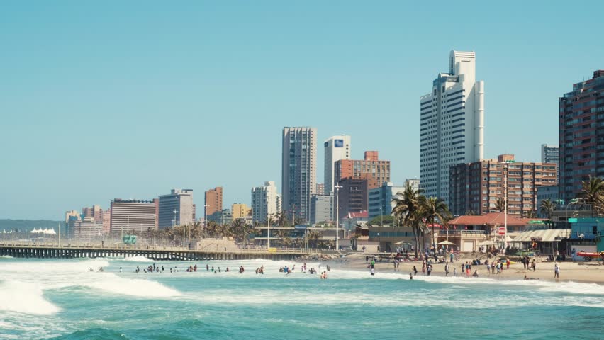 Lust for life beach life in Durban South Afrika. Big waves are crossing the scene and people are playing with the surf.