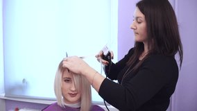 Woman getting new haircut by hairdresser at beauty salon. polishing hair
