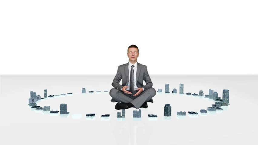 Businessman meditating with buildings rising around him
