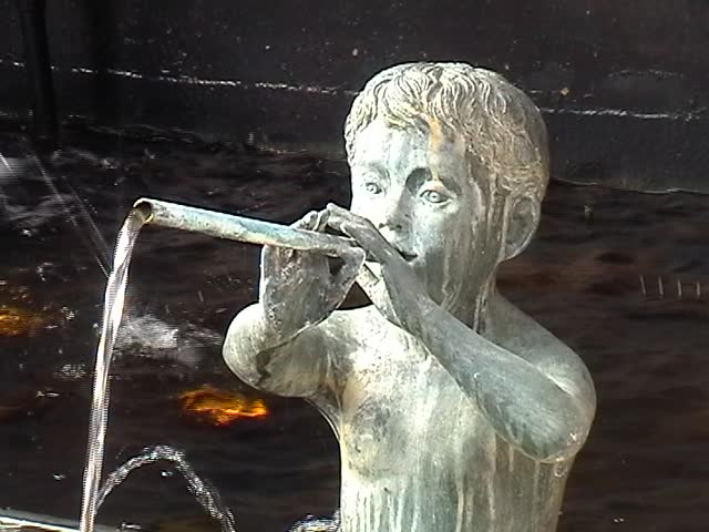 Statue of boy with water coming out of a pipe from his mouth / fountain