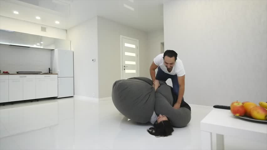 4K Couple fighting over the remote control in front of TV