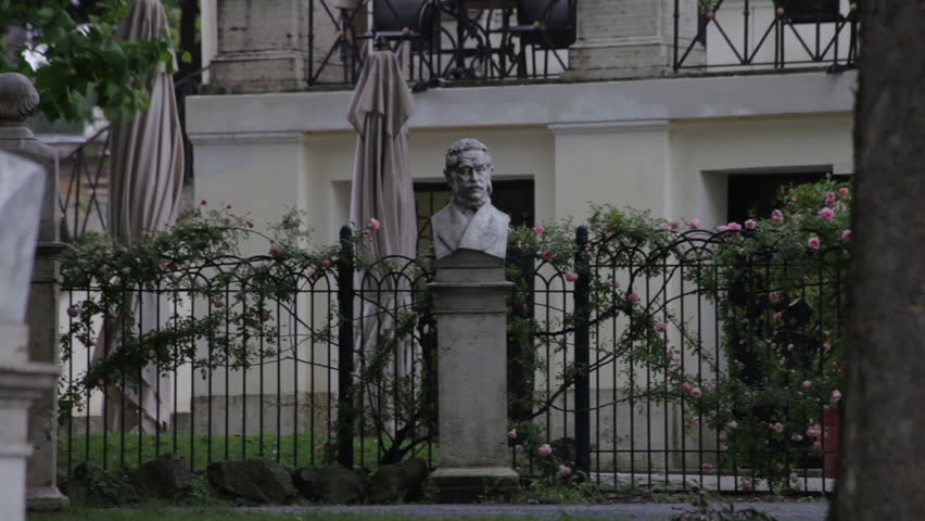 Panning shot of two bust statues in front of a Roman home. 